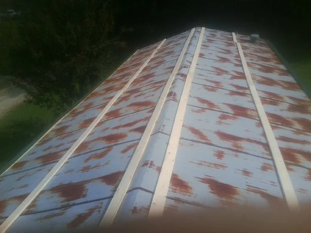 Rusted metal roof panels with new wood purlins before replacement in East Petersburg