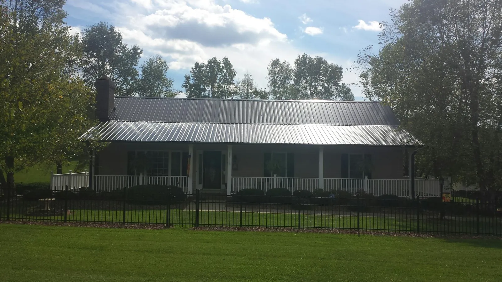 Gray metal roof on a brick ranch with a full width front porch — Gutter Guard Installation work by our crew in East Petersburg