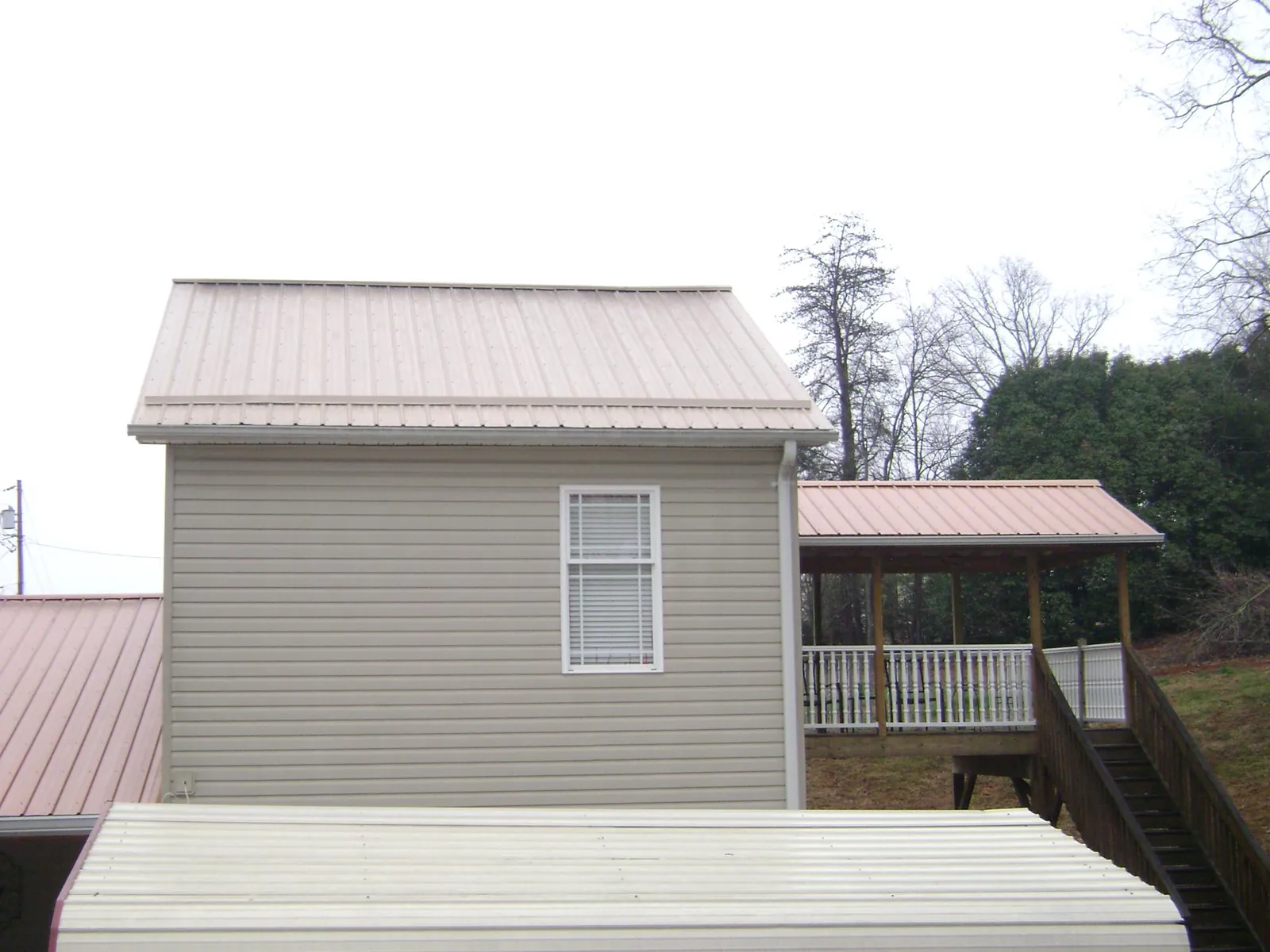 Tan metal roofs on a two story addition and attached porch, from a Roof Replacement job in East Petersburg